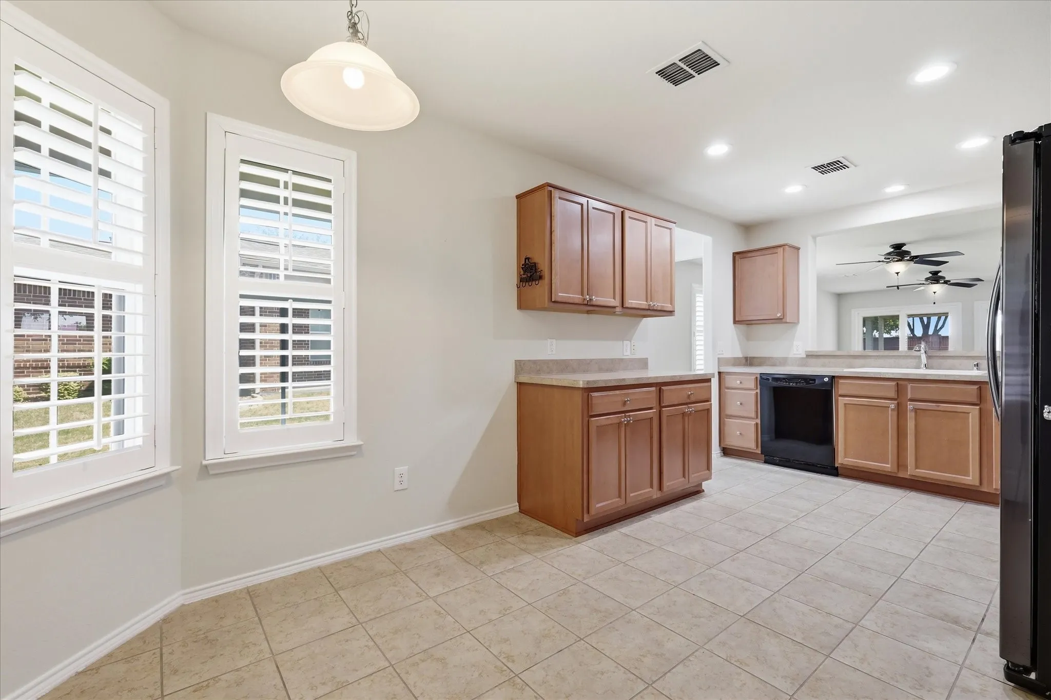 Kitchen featuring tile flooring, wood cabinetry, light-toned countertops, a black appliance suite, and recessed lighting