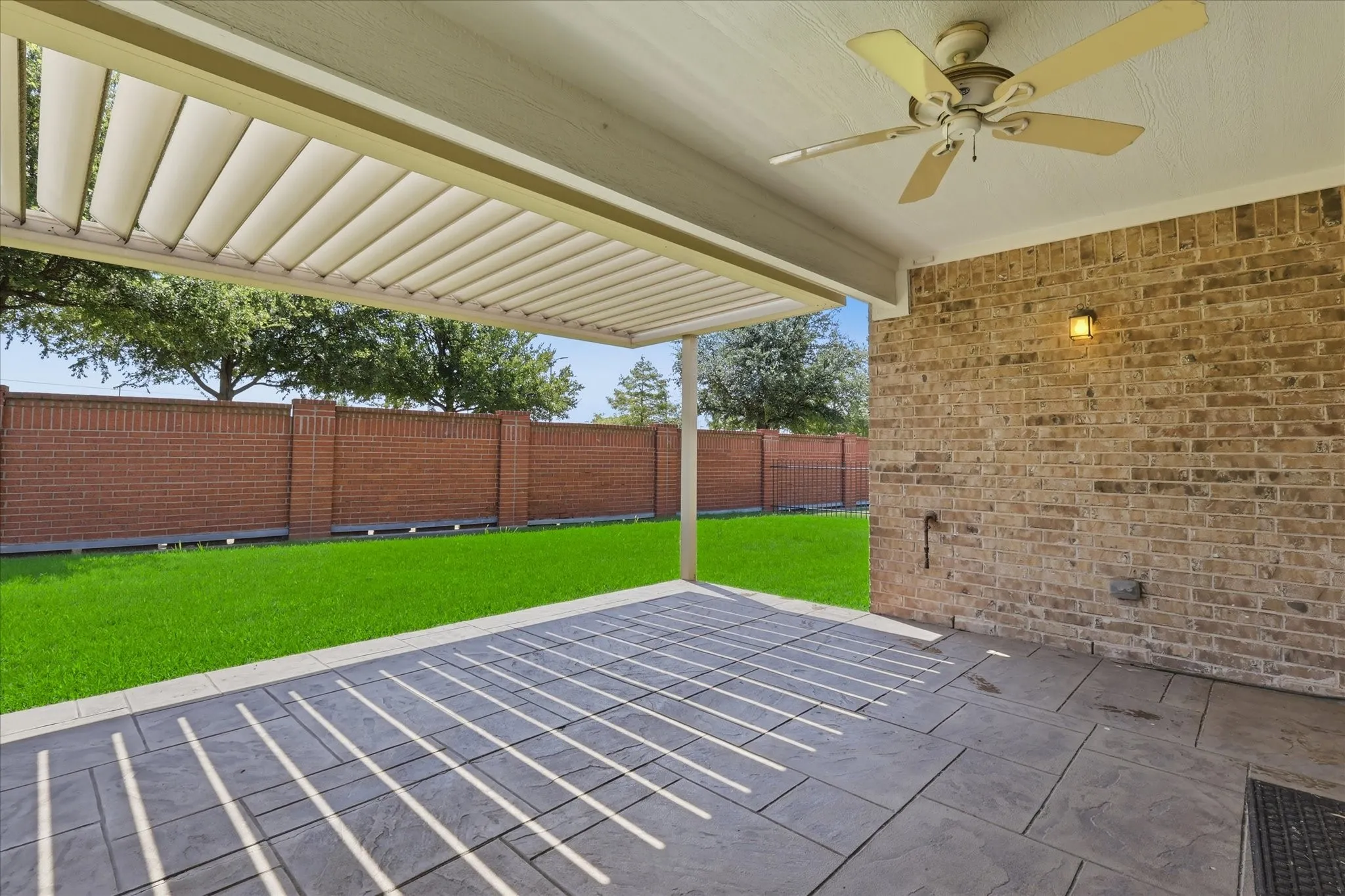 Extended Covered patio with louvered pergola and ceiling fan overlooking expansive lawn