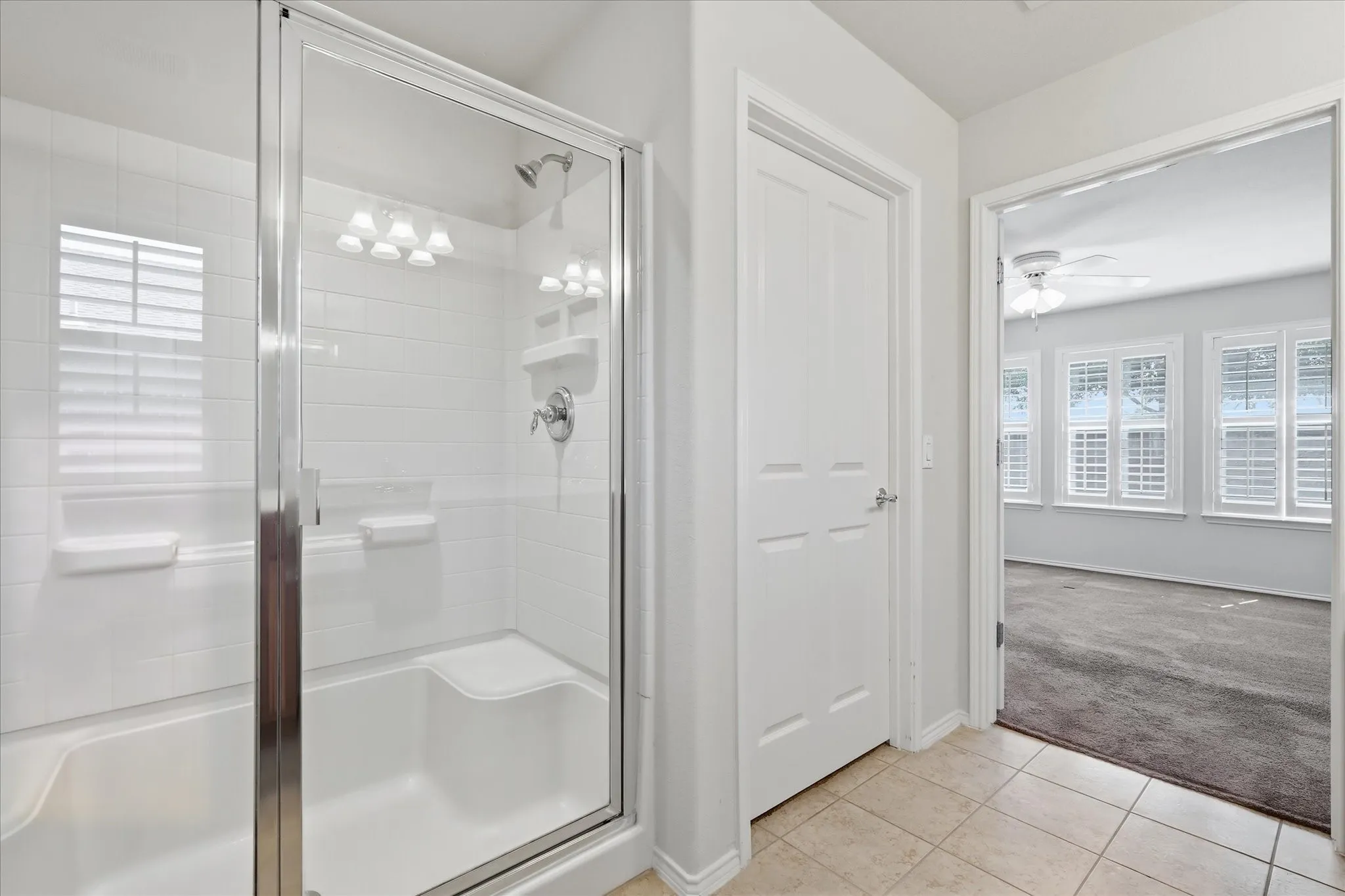 Spa-inspired primary bathroom featuring a frameless glass-enclosed shower with chrome fixtures, white subway tile surround, and recessed lighting