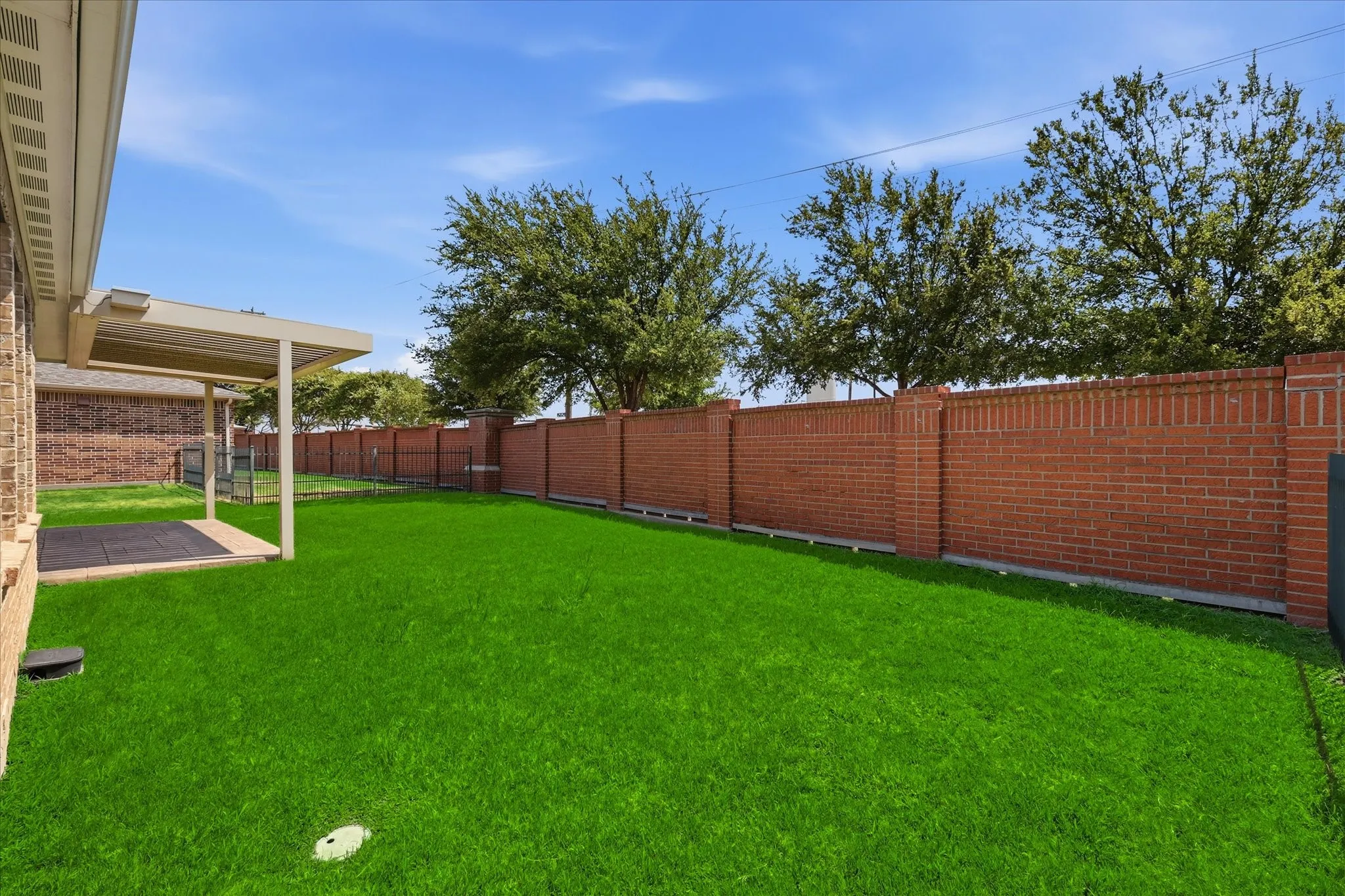 Spacious backyard featuring a covered patio with stamped concrete surface