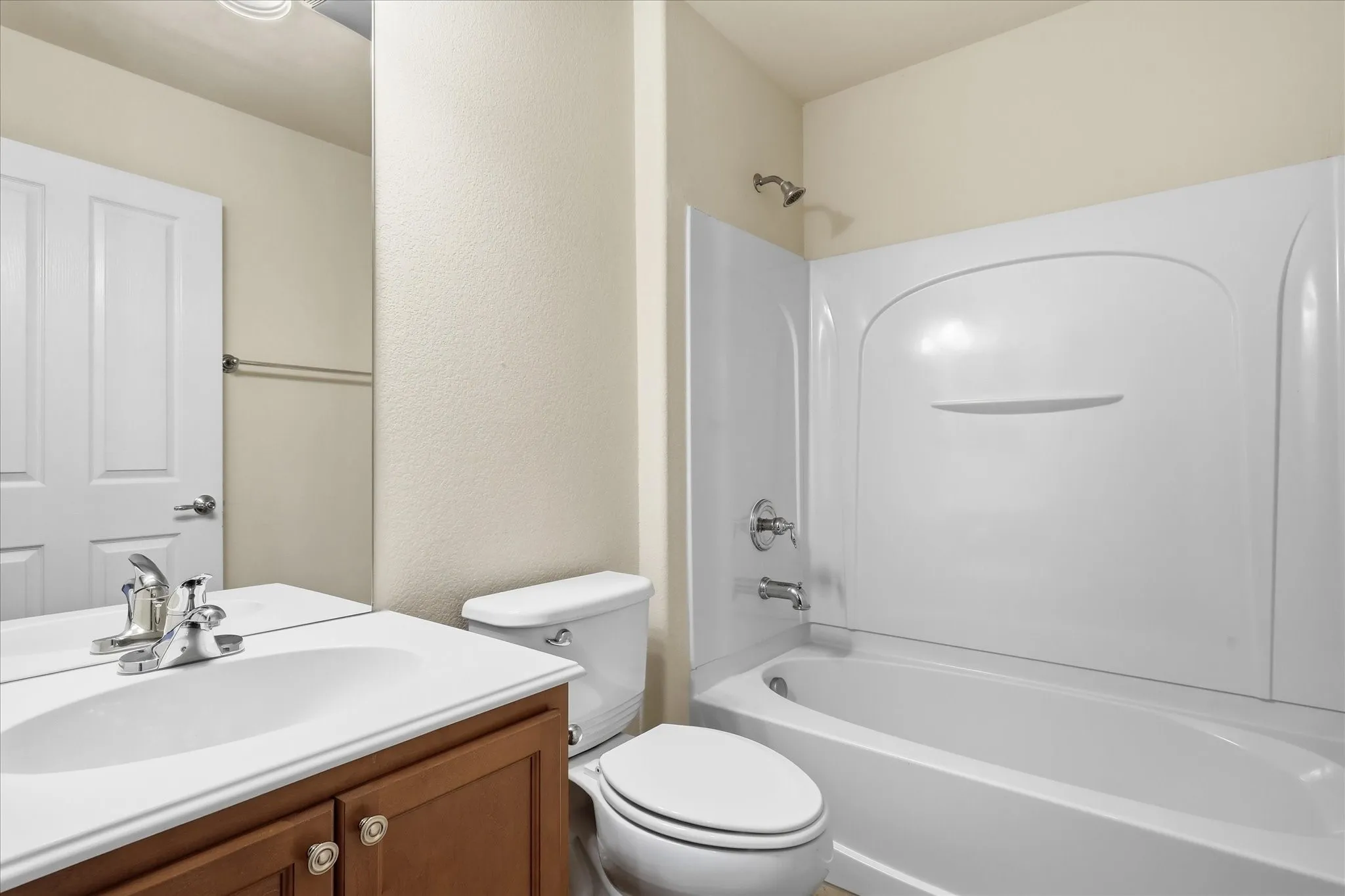 Bathroom featuring a white tub-shower combination with an integrated surround