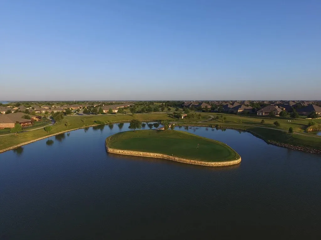Aerial view showcasing the property's distinctive curved landscape design with manicured grounds, multiple water features, and lush green spaces