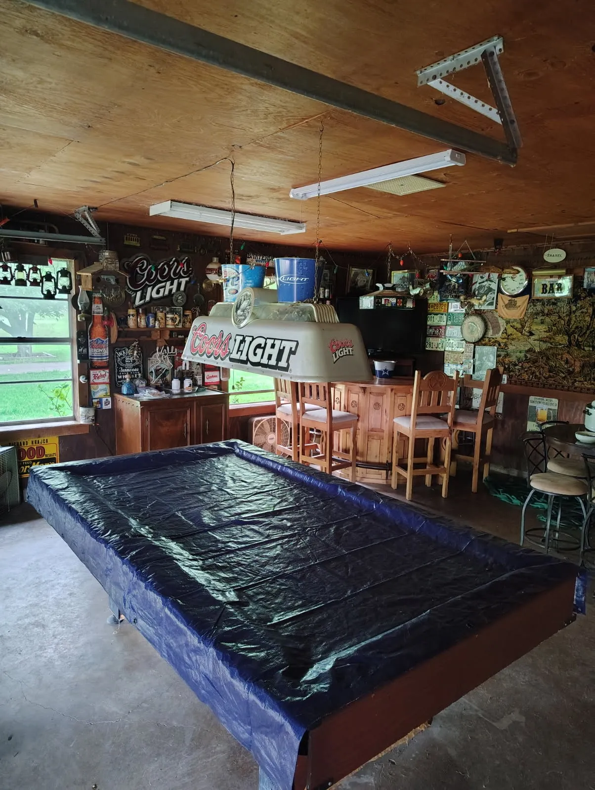Recreational space featuring a built-in bar with wood-finish cabinetry, bar stools, and overhead fluorescent lighting