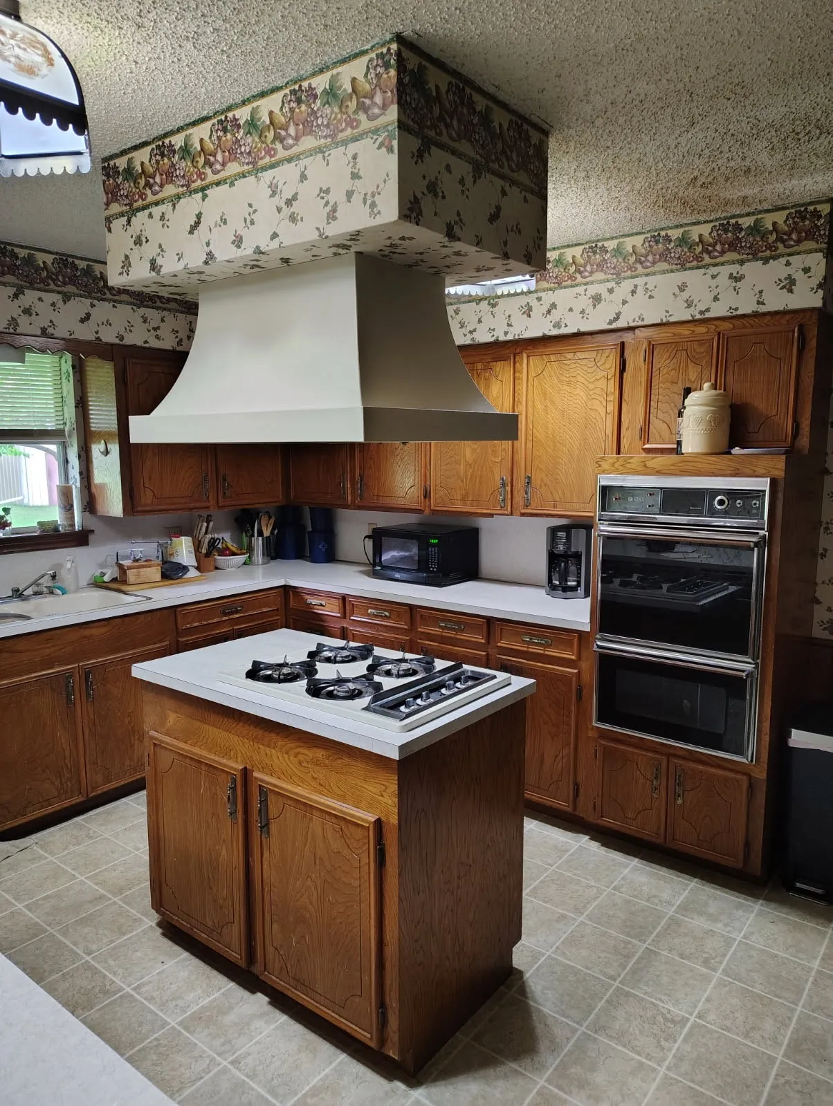 Spacious kitchen featuring wood cabinetry, a center island with gas cooktop, dual wall-mounted ovens, and a professional-style range hood