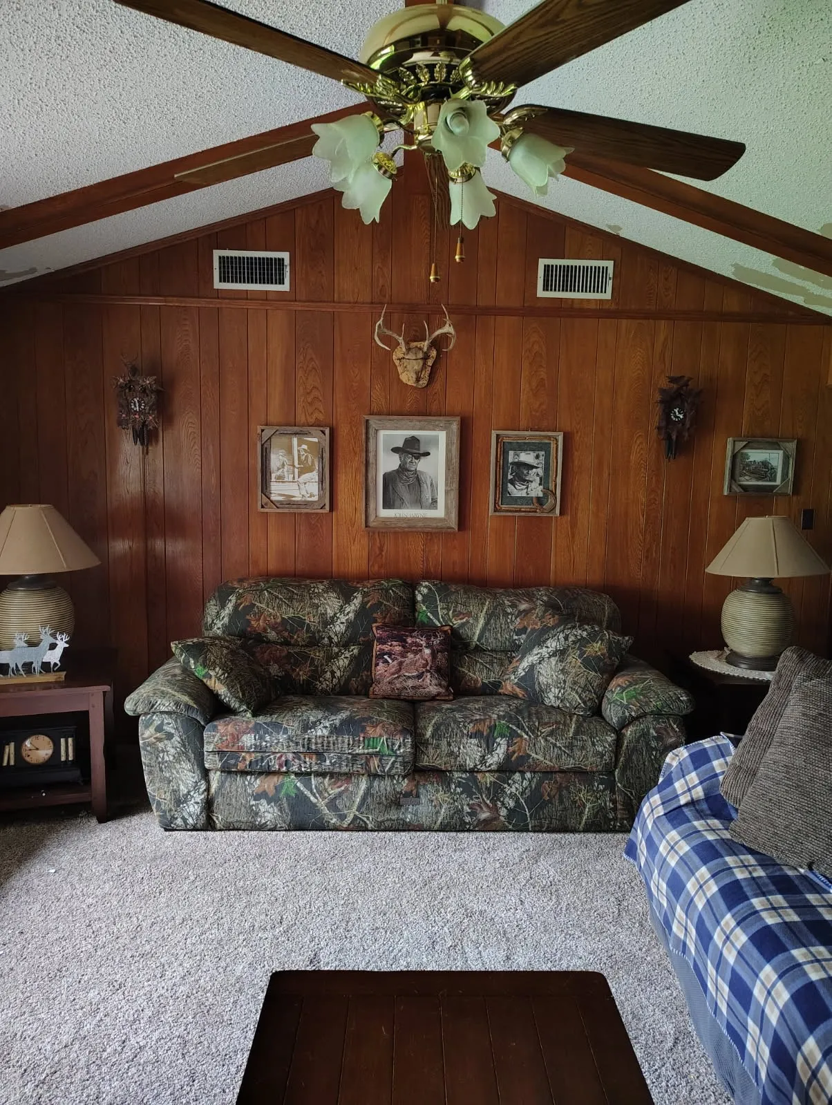 Rustic den featuring rich wood paneling, exposed beam ceiling, and brass ceiling fan