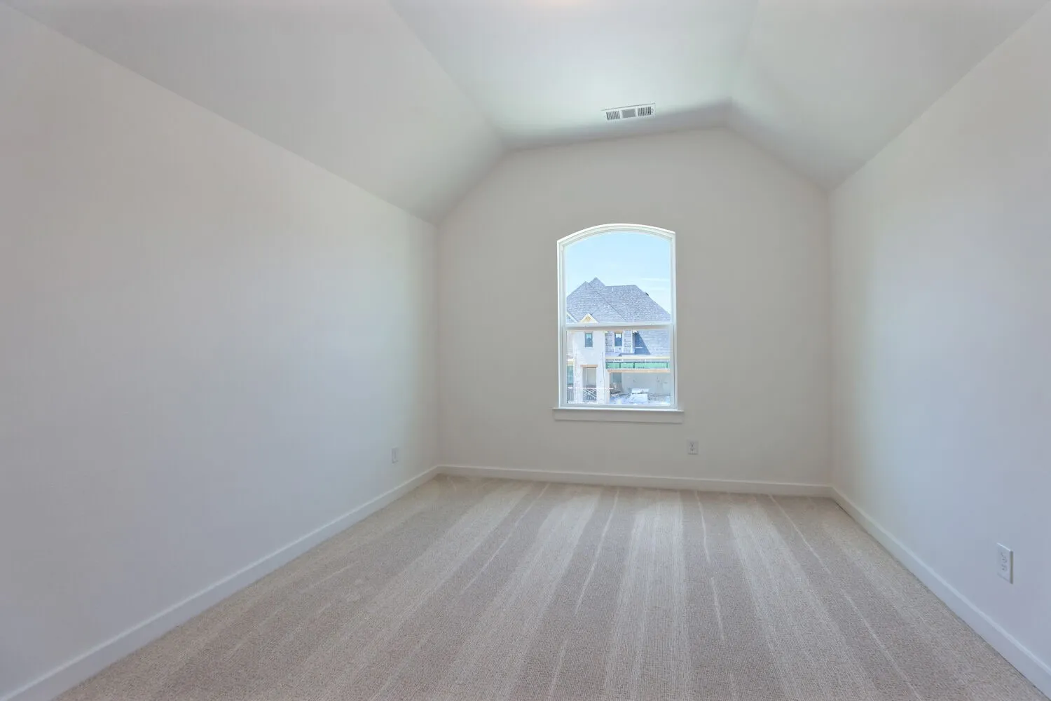 Bright bedroom featuring vaulted ceilings, wood-finish flooring throughout, and a large arched window with natural light and mountain scenery