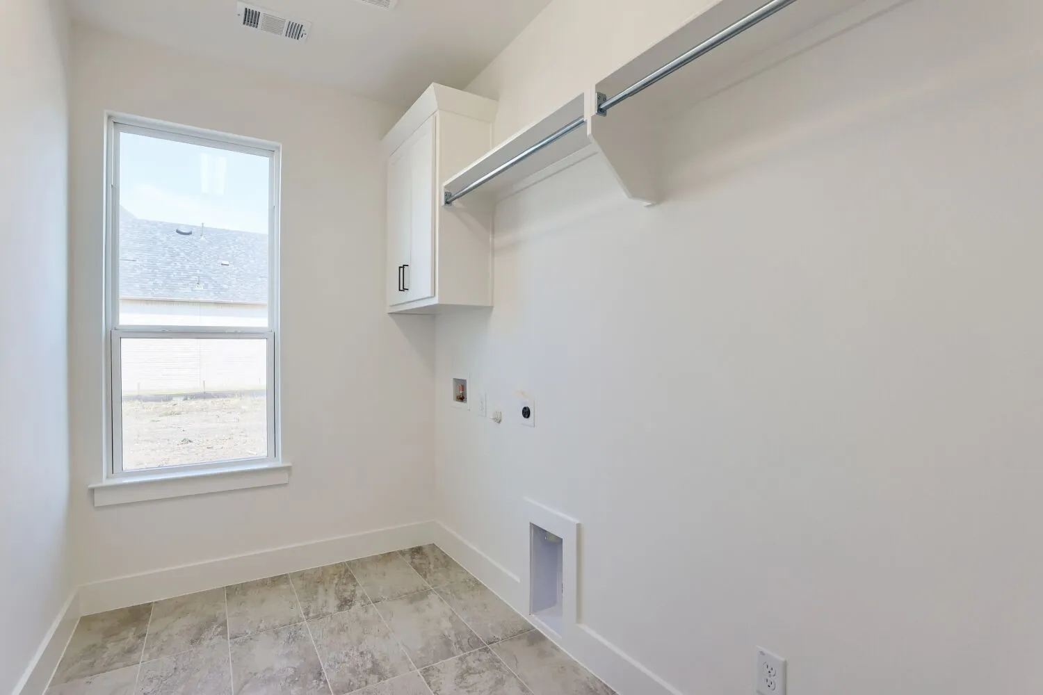 Dedicated laundry room featuring tile flooring, chrome rod closet system, white cabinetry with upper storage, utility outlet access, and a bright window for natural light