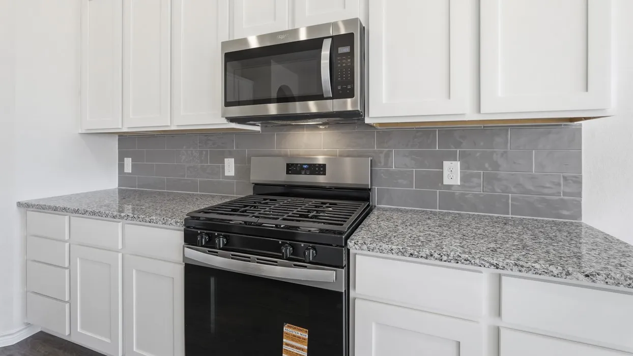 Kitchen featuring white shaker-style cabinetry, granite countertops, a stainless steel gas range, a stainless steel over-the-range microwave, and a gray subway tile backsplash