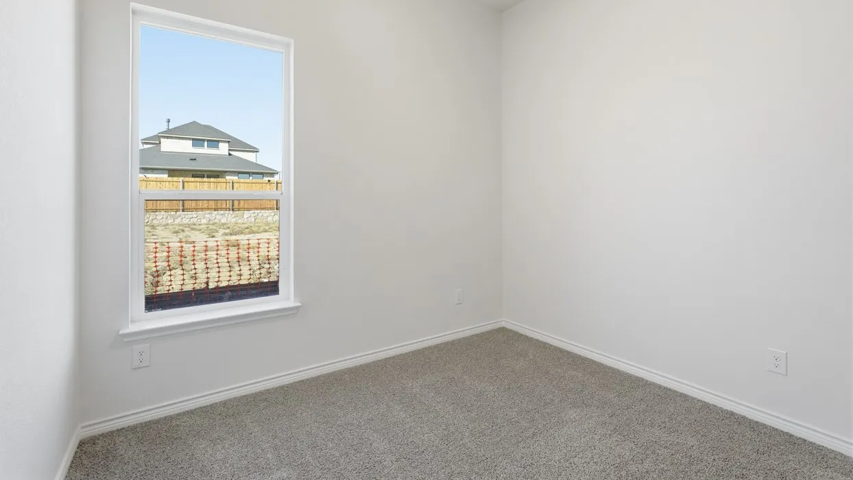 Bright bedroom with neutral wall finishes, plush carpeting, and a large window framing neighborhood scenery and natural light