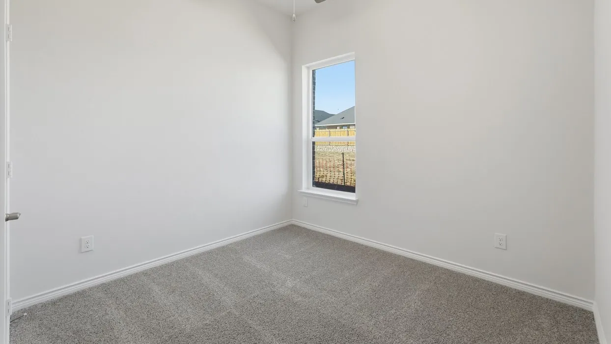 Bright corner bedroom with plush carpeting, clean white walls, and a tall window framing natural light and scenic mountain backdrop