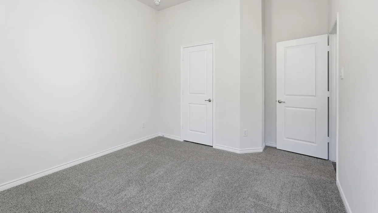 Neutral tone-on-tone room featuring plush gray carpeting, white baseboards, and two paneled interior doors with brushed nickel hardware