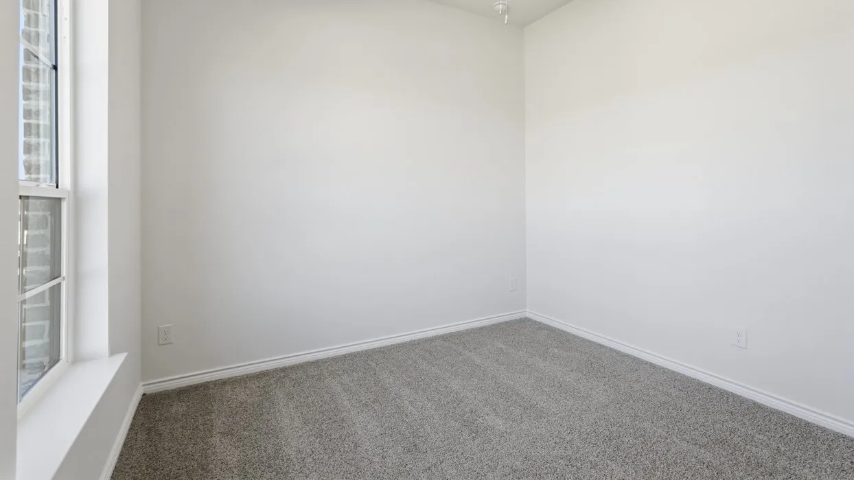 Bright corner bedroom with neutral wall finishes, generous natural light from large window, and neutral carpet flooring throughout