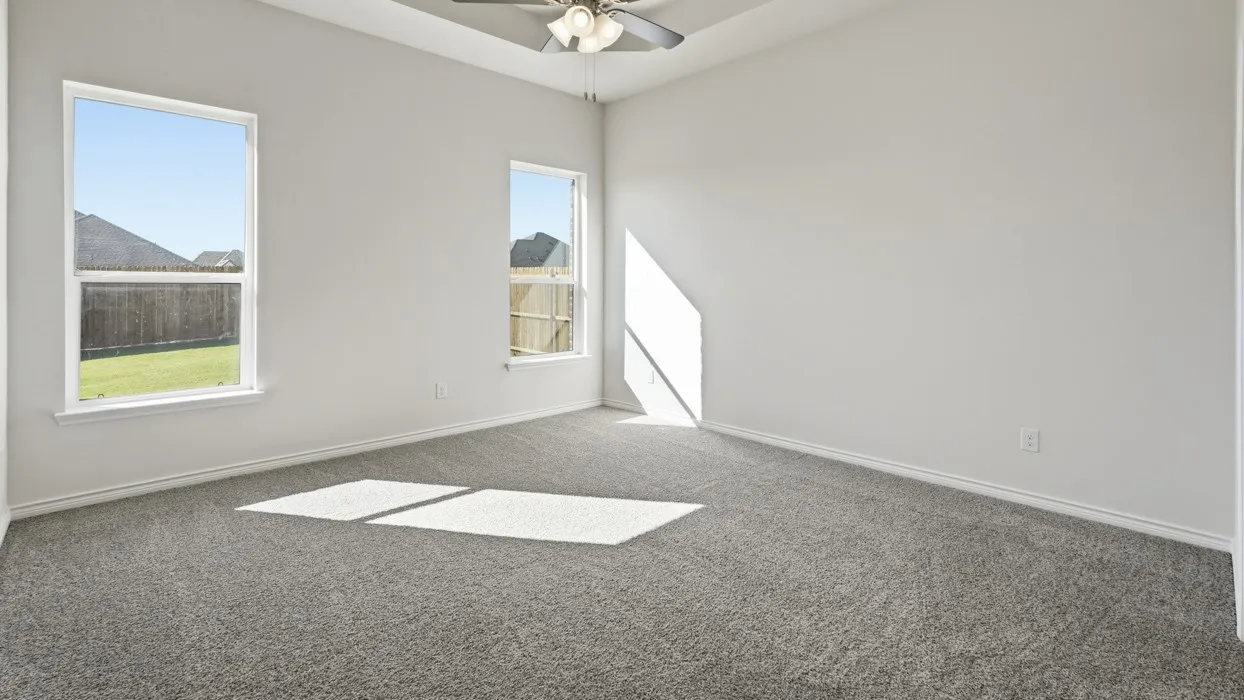 Bright and airy bedroom featuring neutral carpeting, abundant natural light from dual windows, and ceiling fan fixture