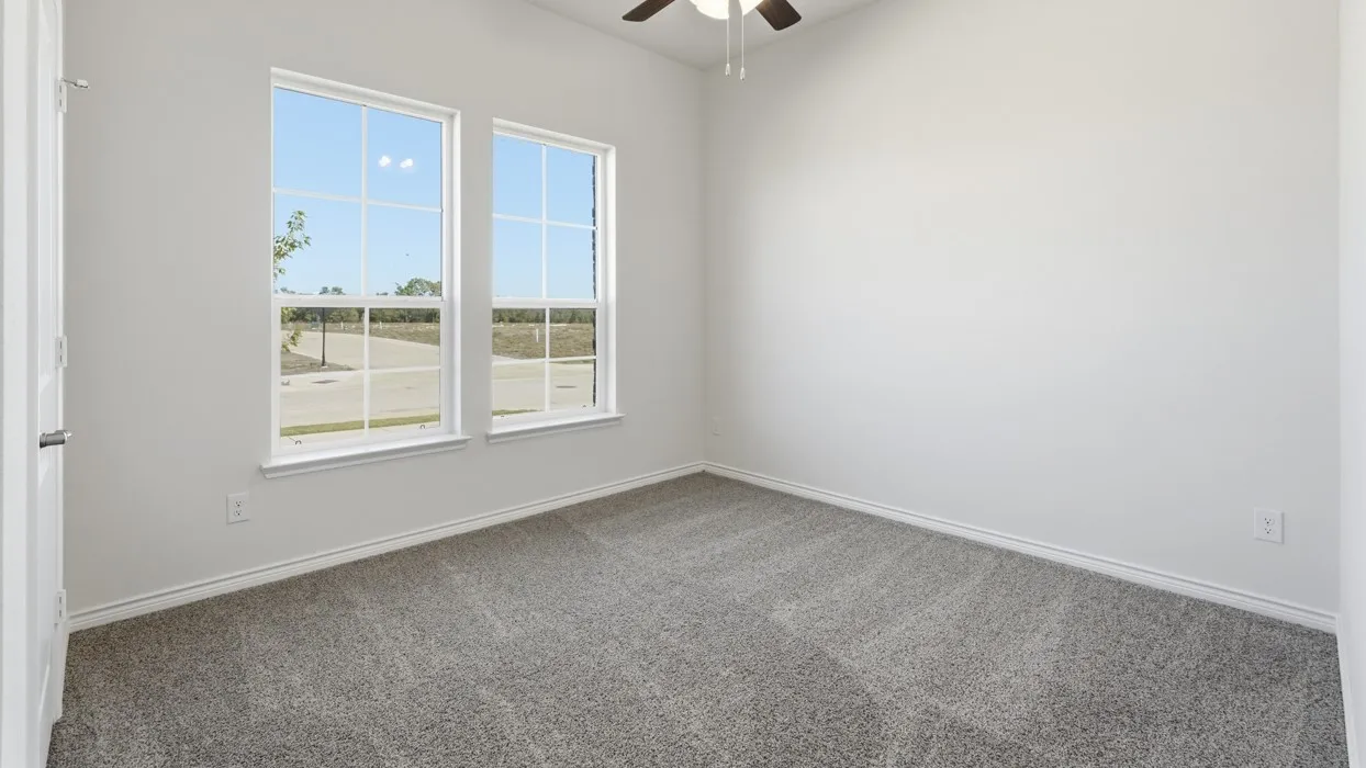 Room featuring two large grid-pattern windows, light gray wall paint, gray carpet flooring, and a ceiling fan with integrated lighting
