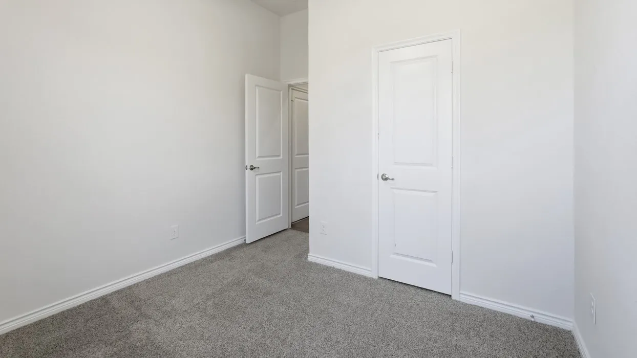 Spacious bedroom featuring neutral wall finishes, plush carpeting, and dual closet access including a walk-in option