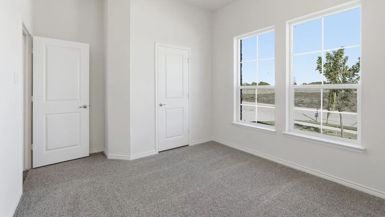 Bright interior room featuring a neutral color palette, two large windows with grid inserts, gray carpet flooring, white trim, and white paneled doors