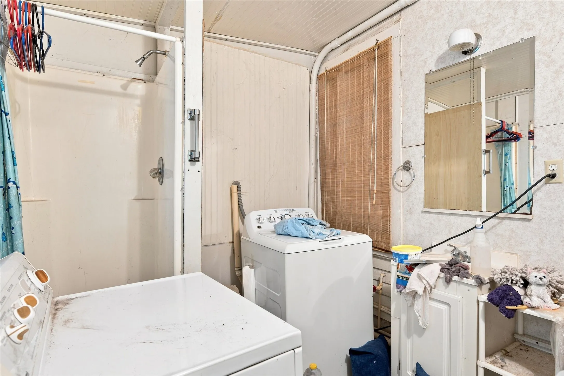 Functional bathroom featuring a full bathtub with shower enclosure, pedestal sink, large wall-mounted mirror, and ample storage cabinetry