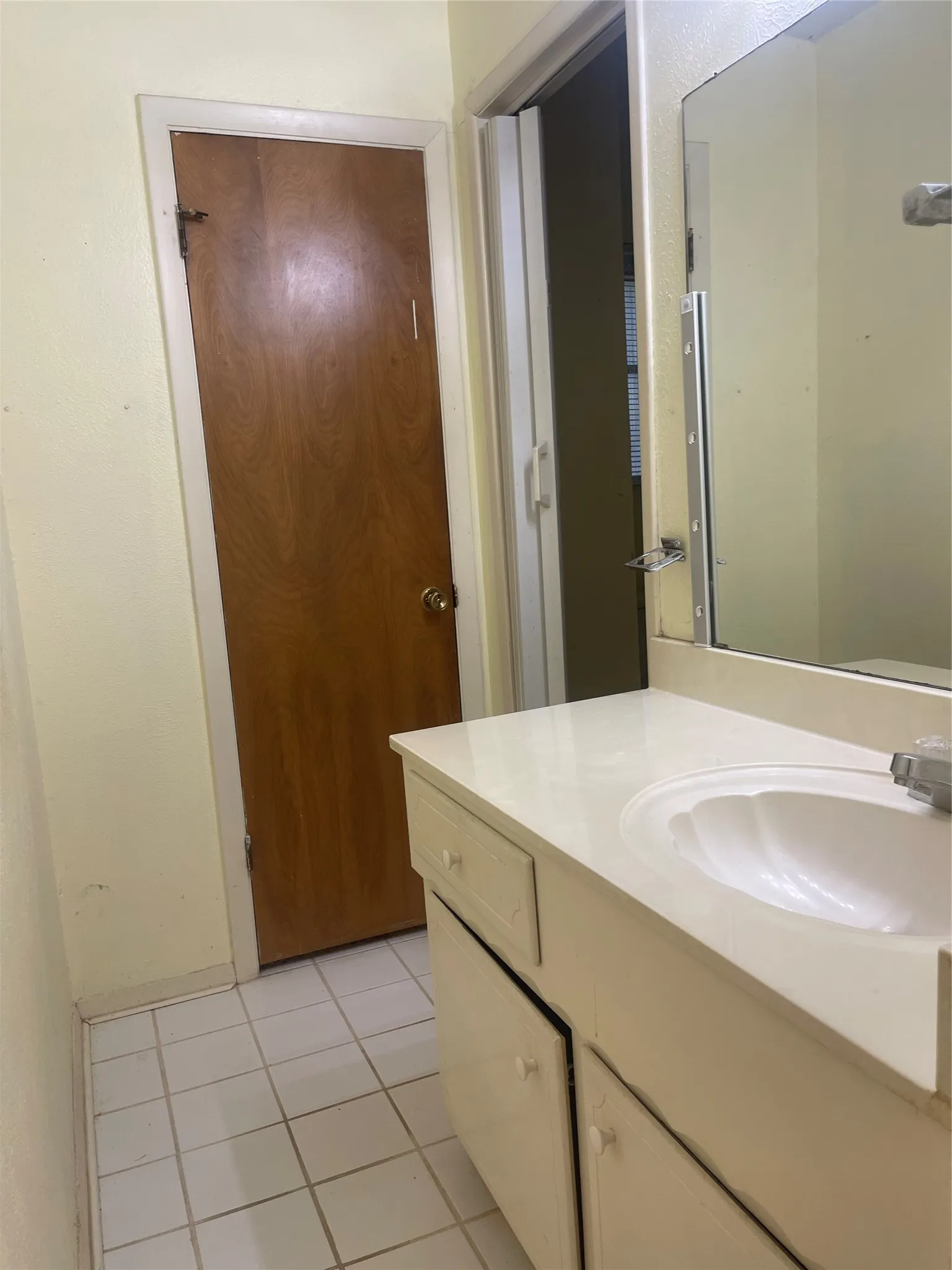 Bathroom featuring a ceramic tile floor, vanity with integrated sink and countertop storage, large mirror with framed surround, and brushed nickel hardware