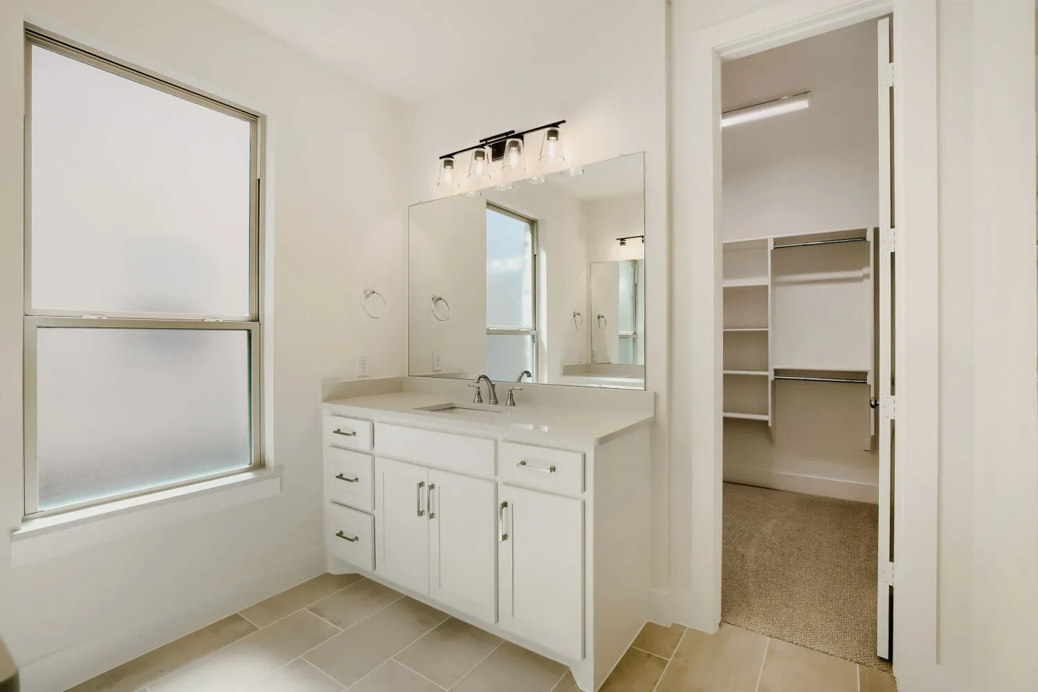 White vanity with a single basin, ample storage cabinetry, and a countertop