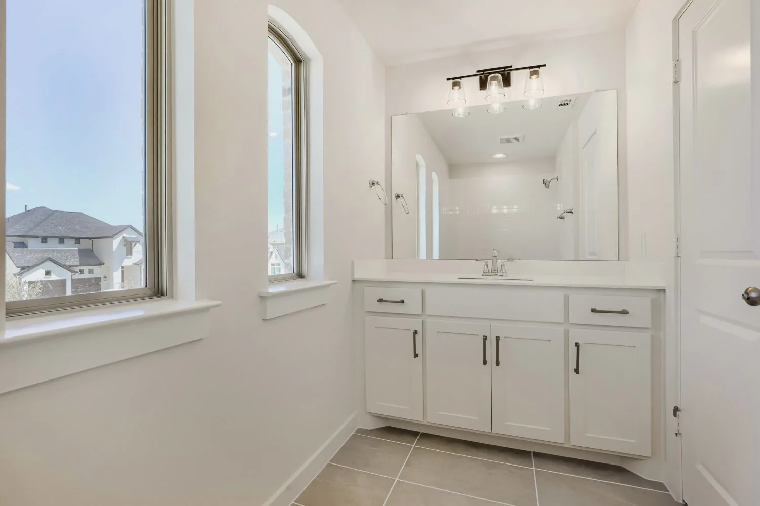 White vanity with under-sink storage, a rectangular mirror, and a three-light vanity fixture