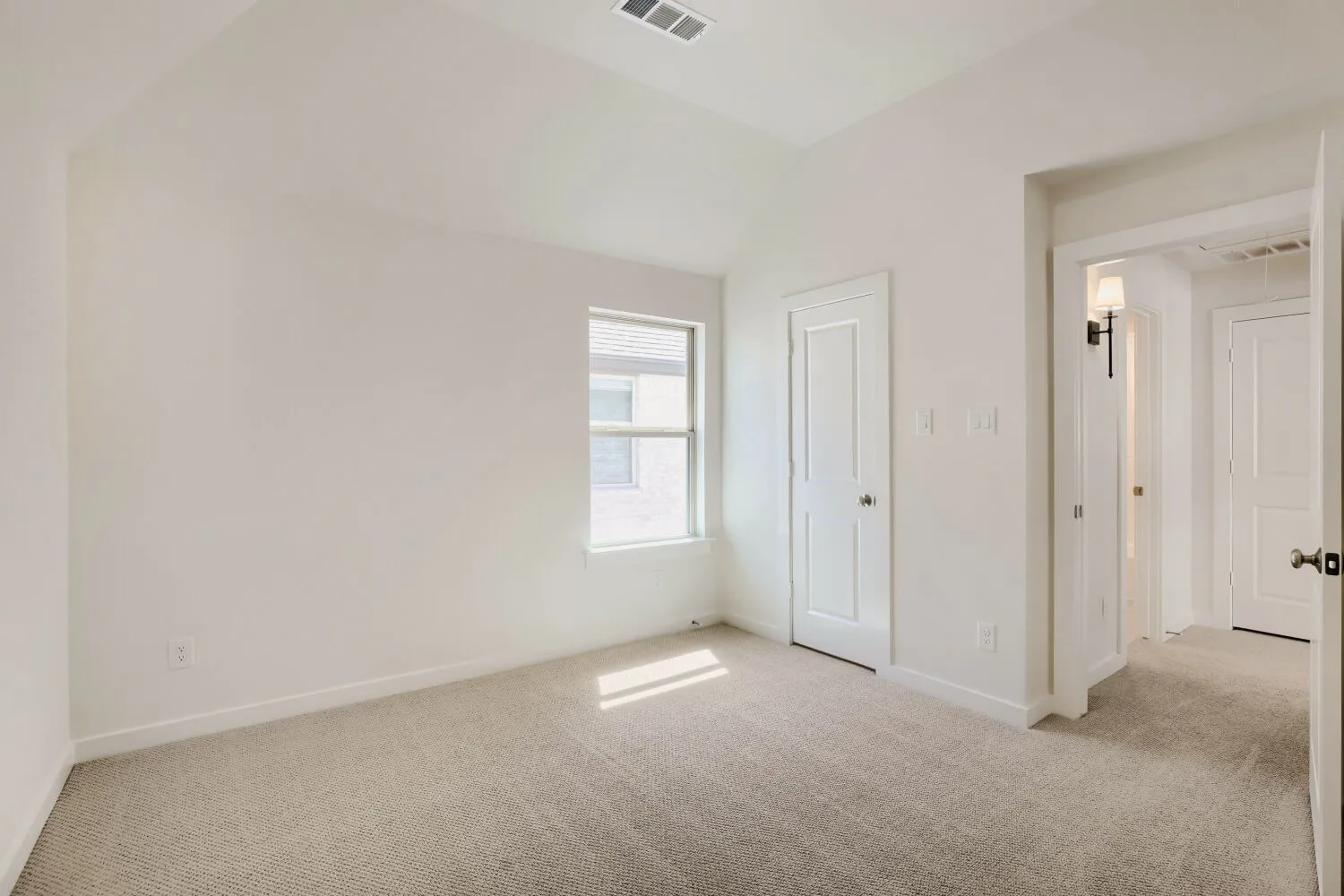 Neutral carpet flooring, white painted walls, white trim, single window, and a white paneled door