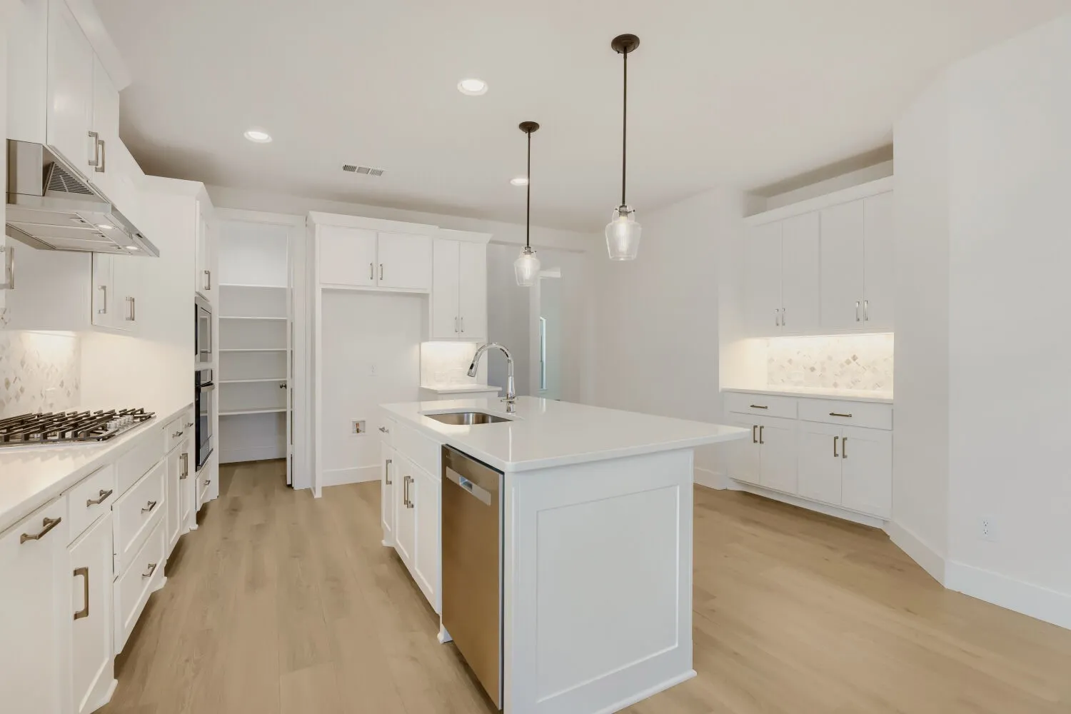 Modern kitchen featuring a gas cooktop, built-in oven, stainless steel dishwasher, and a large island with sink