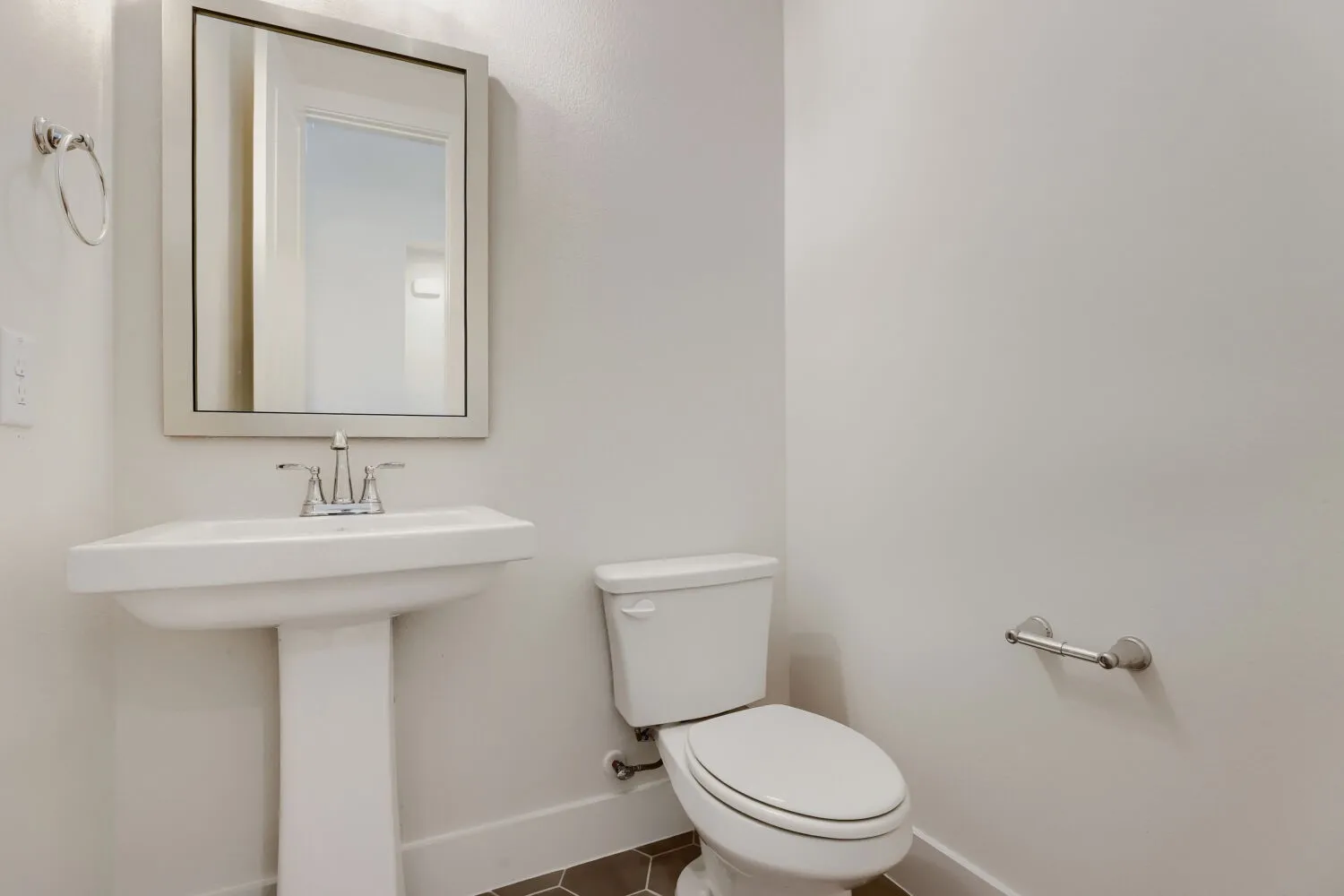 Pedestal sink with chrome faucet, framed mirror, and hexagonal floor tiling