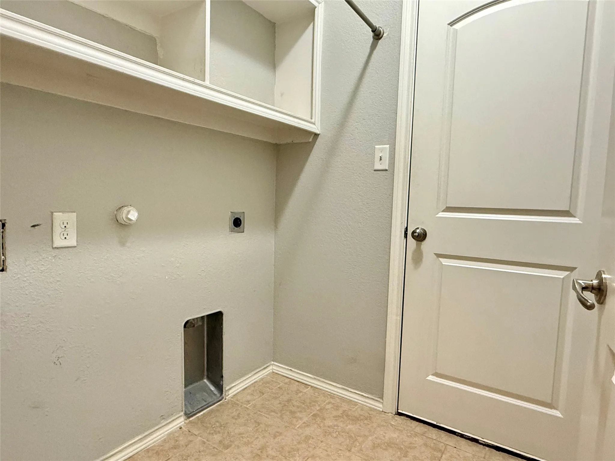 Utility room featuring cork-finish flooring, wall-mounted electrical outlets, shelving with mirrored cabinet storage, and a pet door opening to exterior access