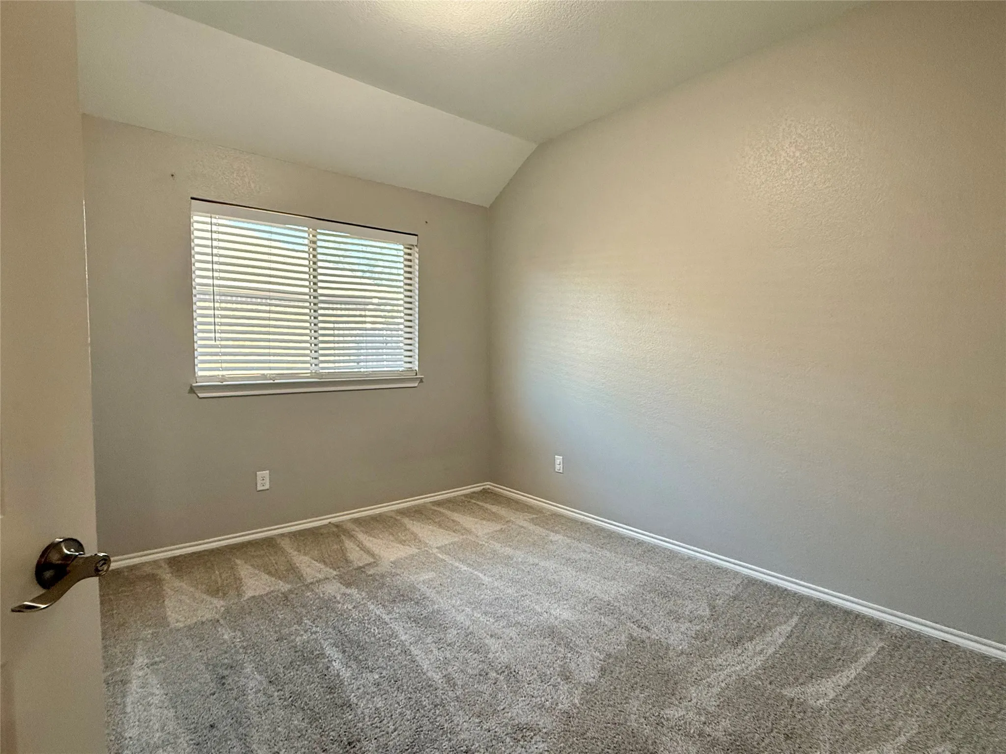 Carpeted room with a single window featuring horizontal blinds