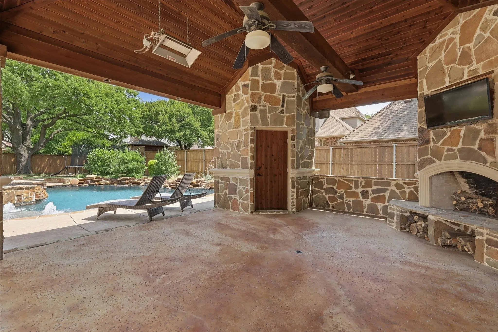 This outdoor kitchen and living area make poolside entertaining a breeze: fireplace, TV, grill, refrigerator, heaters and fans and a half bath!