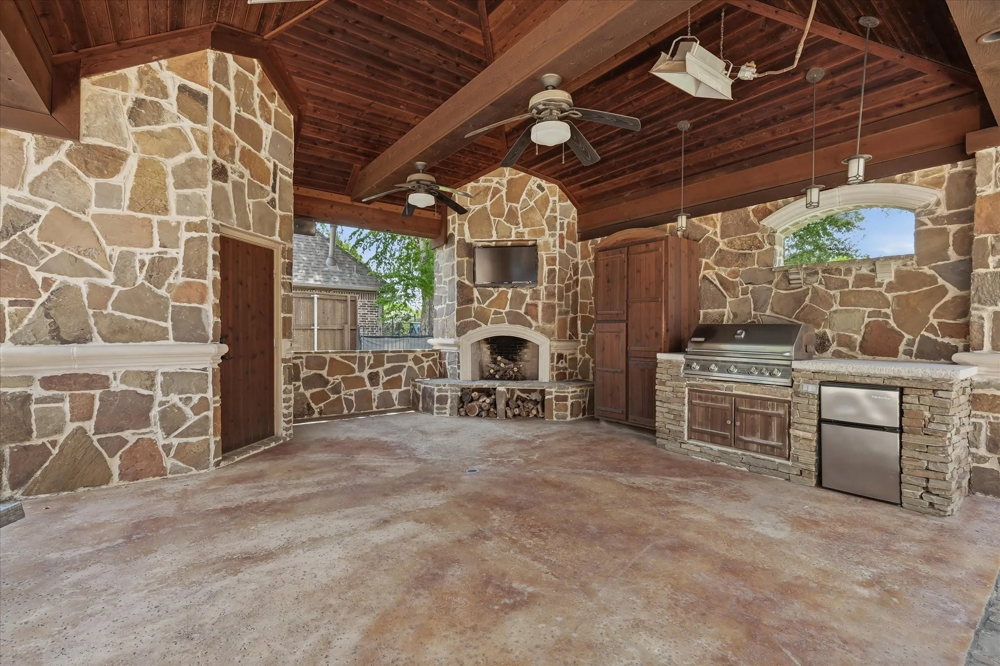 This outdoor kitchen and living area make poolside entertaining a breeze: fireplace, TV, grill, refrigerator, heaters and fans and a half bath!