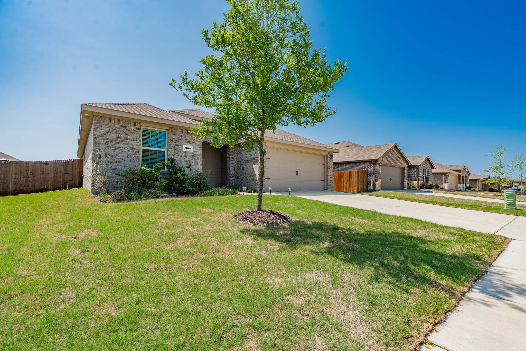 Ranch-style house with concrete driveway, fence, a front lawn, brick siding, and a garage