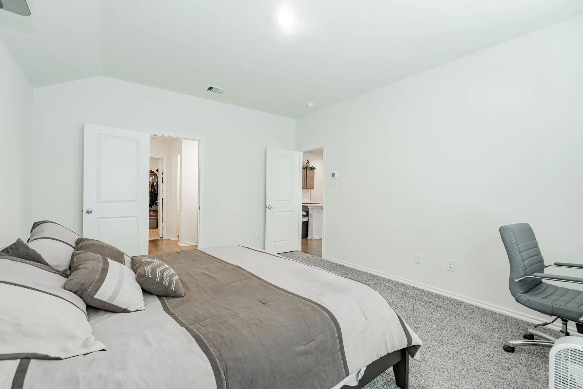 Bedroom featuring baseboards, lofted ceiling, visible vents, and light colored carpet