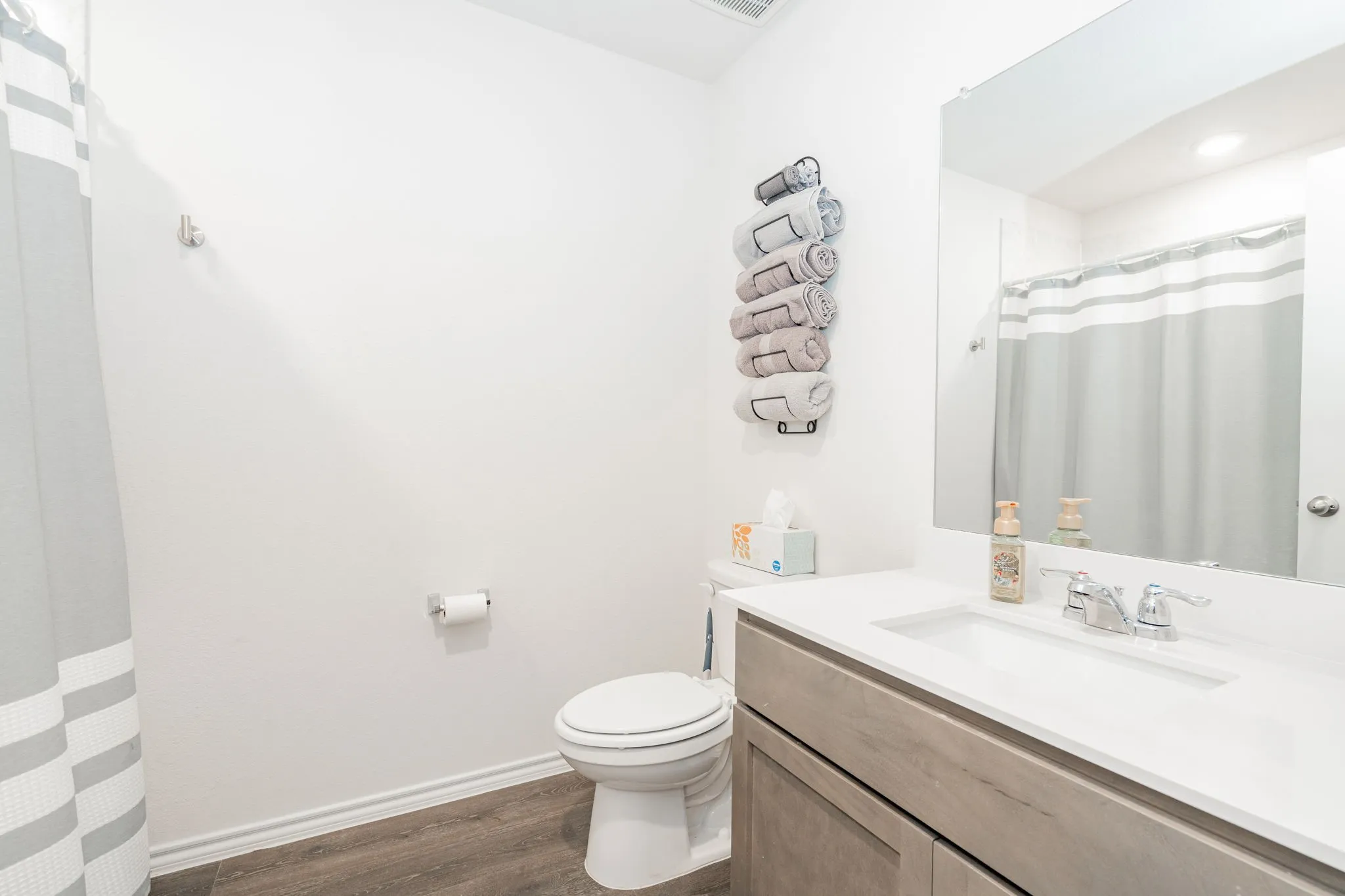 Bathroom with toilet, vanity, a shower with curtain, wood finished floors, and baseboards