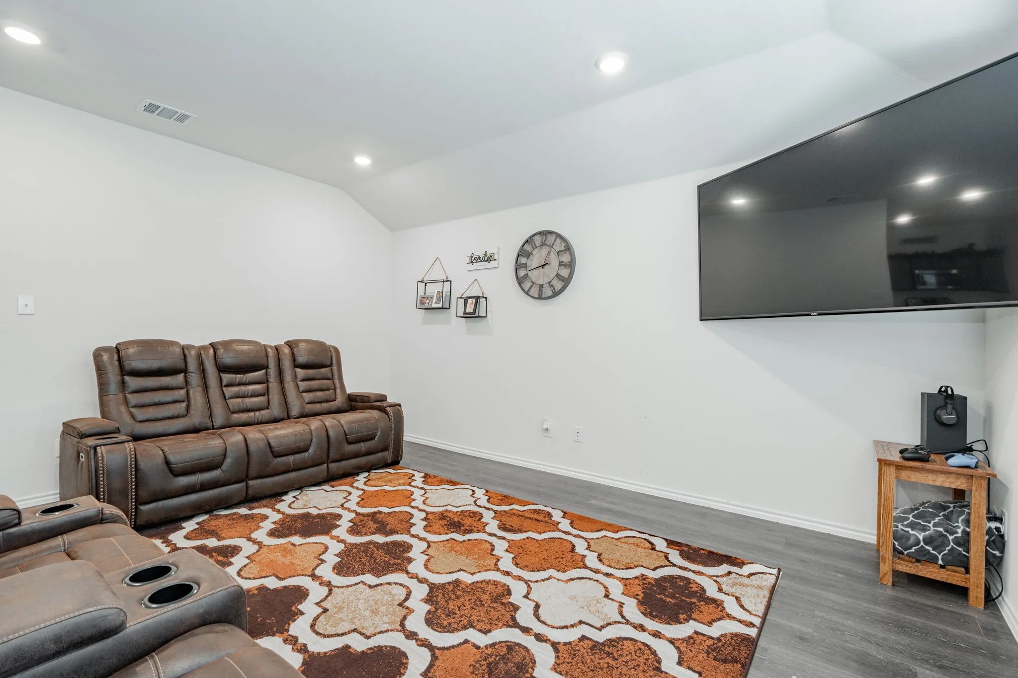Living area with vaulted ceiling, recessed lighting, baseboards, visible vents, and wood finished floors