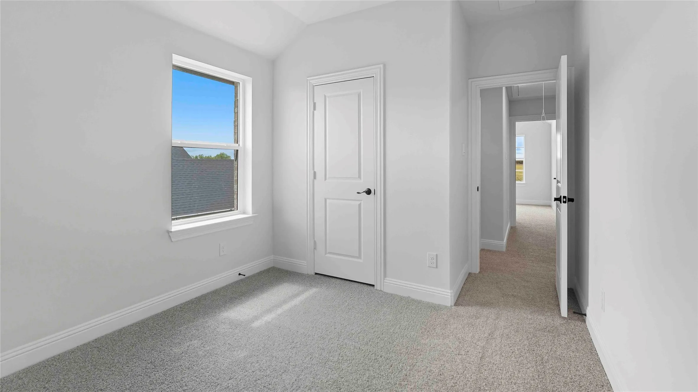 Bright secondary bedroom featuring neutral carpeting, a large window with natural light, white six-panel closet door, and clean white walls