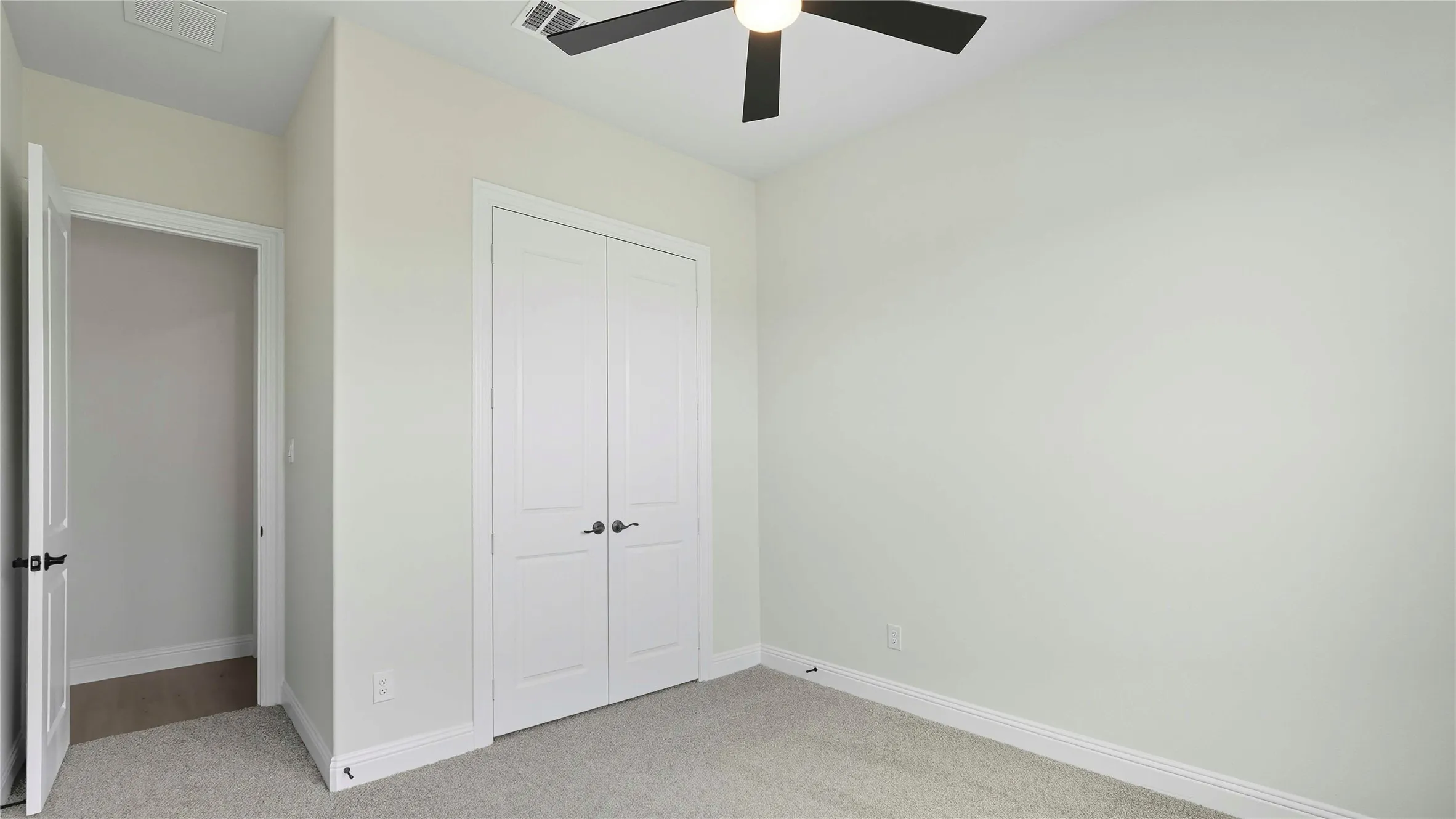 Room featuring light-toned walls, gray carpet flooring, and white baseboards