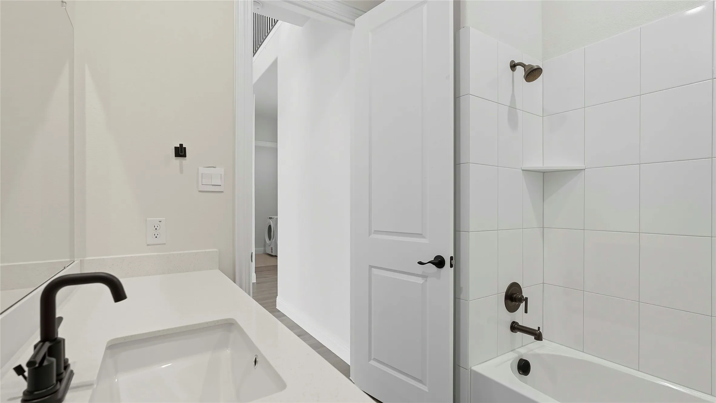 Bathroom featuring a white vanity with an undermount sink, a dark bronze faucet, and a tiled shower-over-tub with a built-in niche