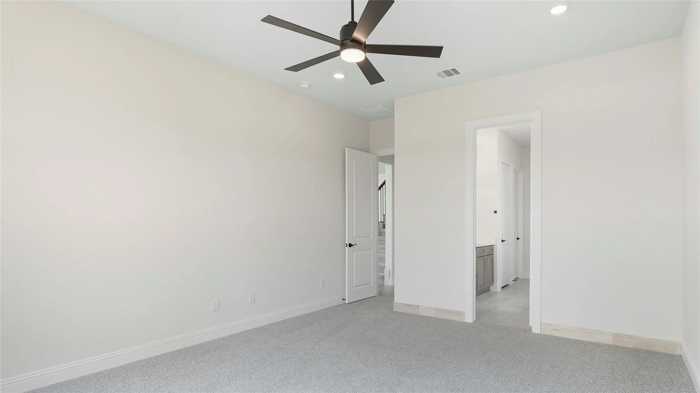 Spacious room featuring neutral carpet flooring, a contemporary ceiling fan, and recessed lighting