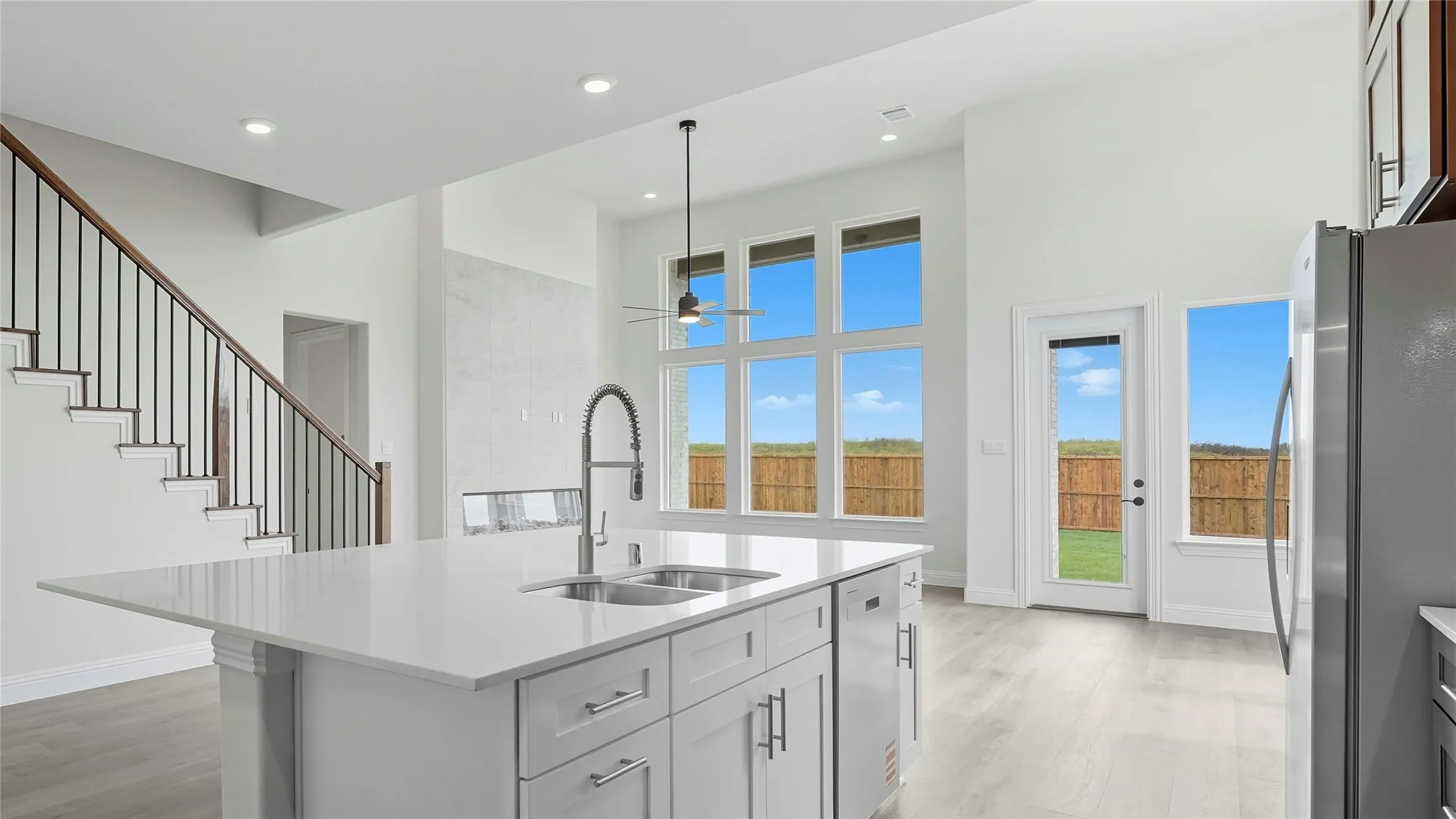 Modern kitchen featuring a large center island with gray cabinetry, white quartz countertop, and an undermount sink with a gooseneck faucet