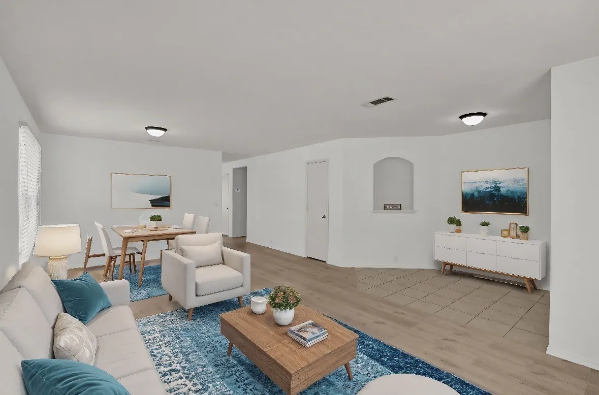 Spacious open-concept living area featuring wood-finish flooring, recessed ceiling lighting, and multiple seating zones anchored by a wooden coffee table