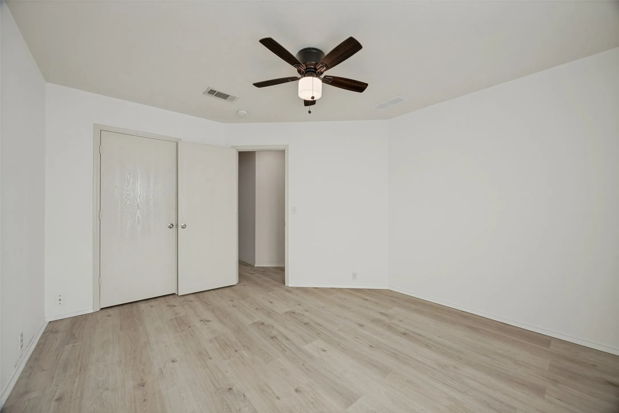 Spacious room featuring light wood-finish flooring and crisp white walls
