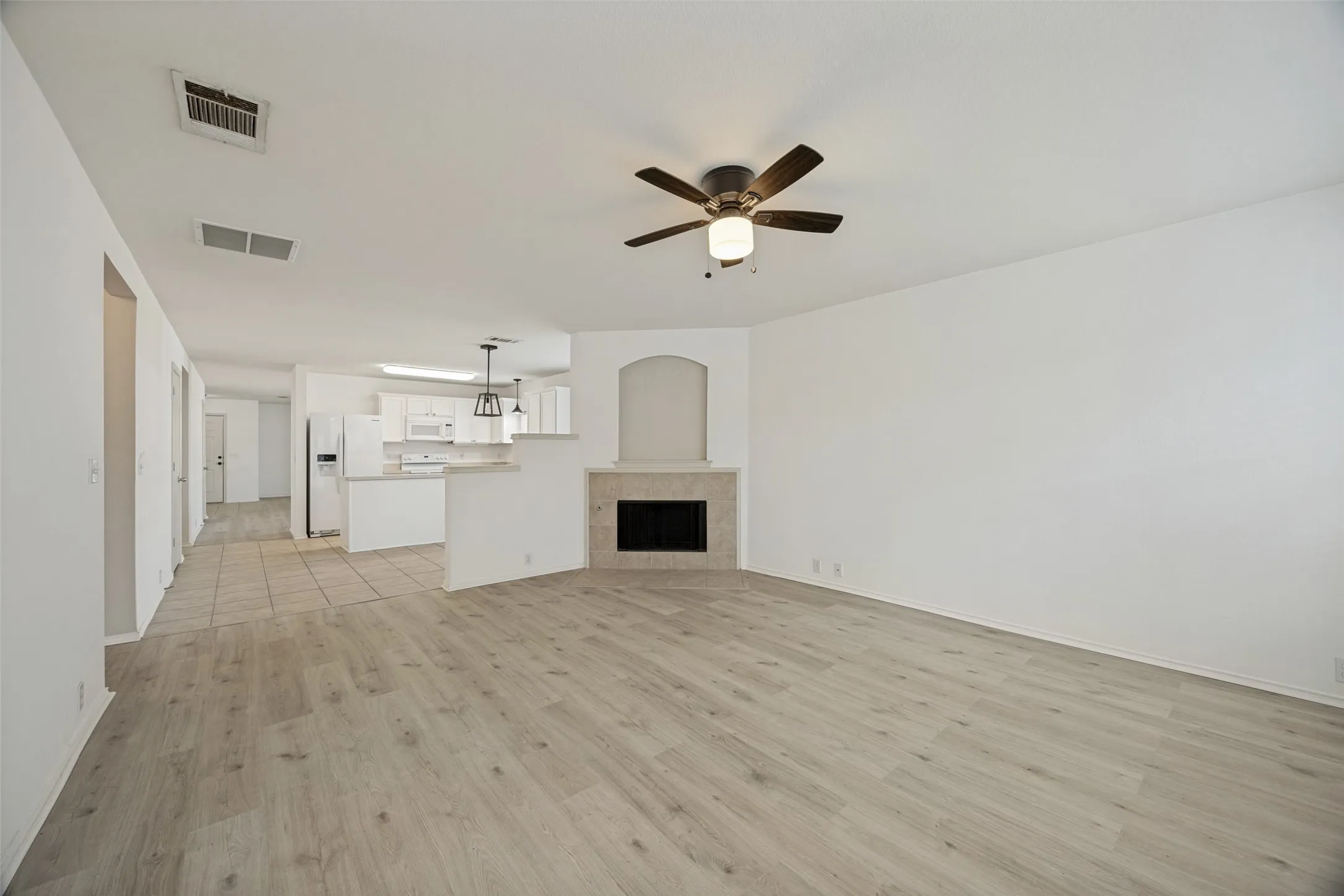 Spacious living area featuring wood-finish flooring and a ceiling fan