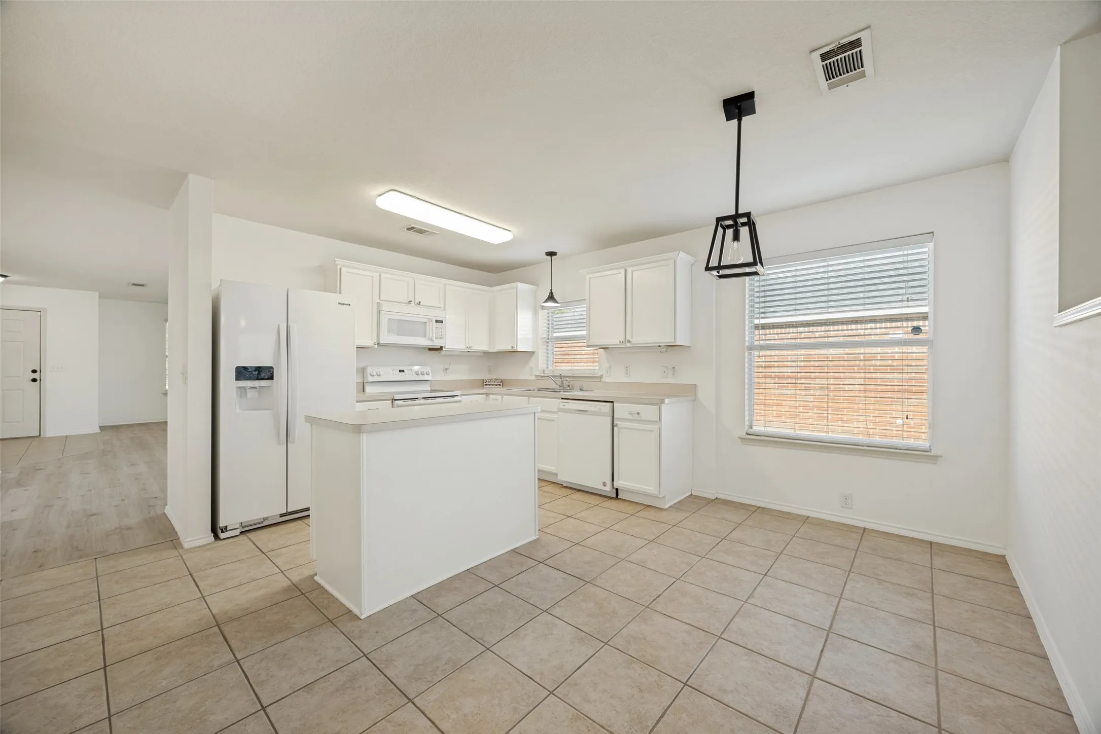 Kitchen featuring white cabinetry, a central island, tile flooring, and white appliances