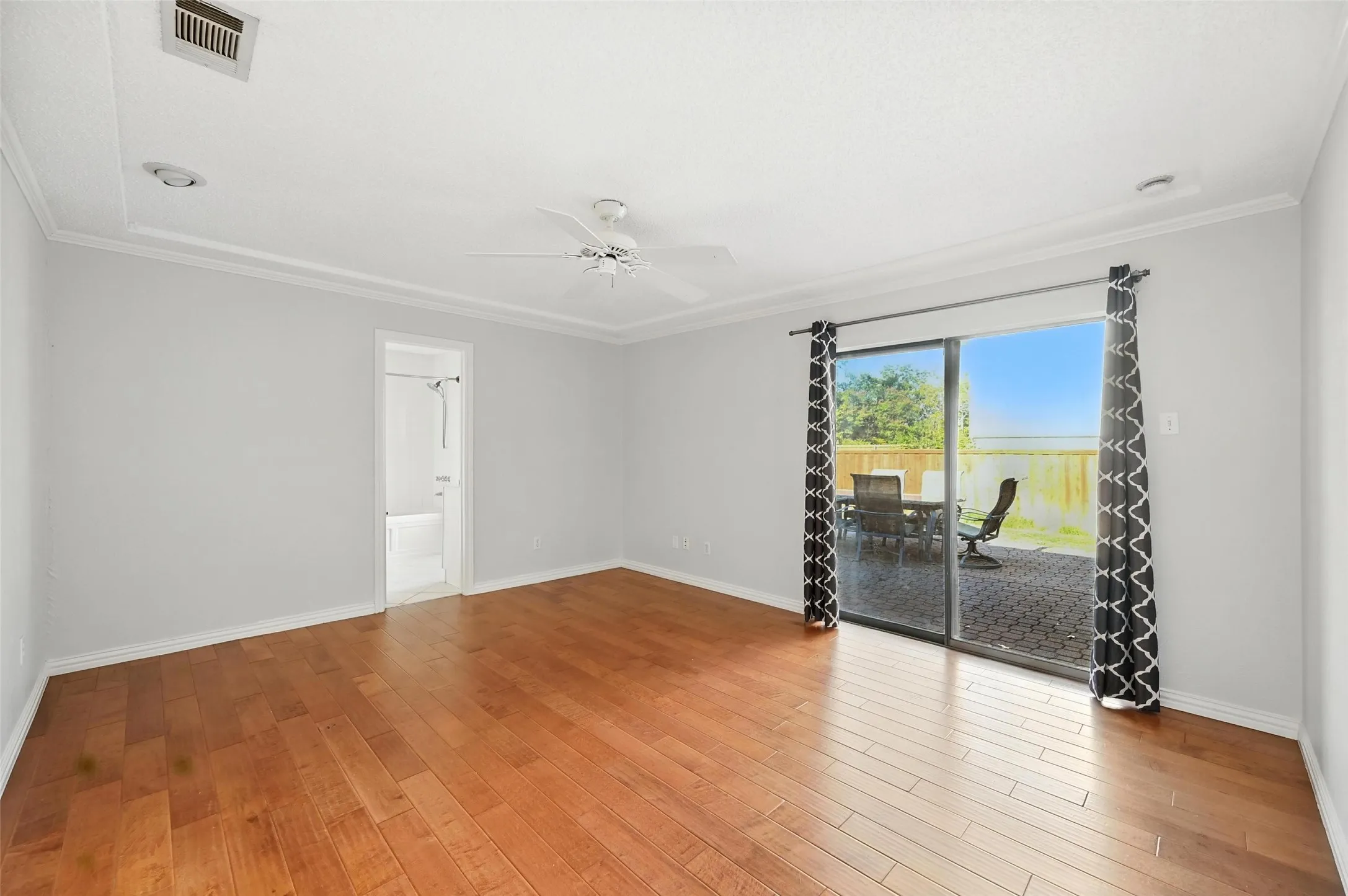 Spacious living area showcasing warm wood-finish flooring, white walls, and recessed ceiling lighting