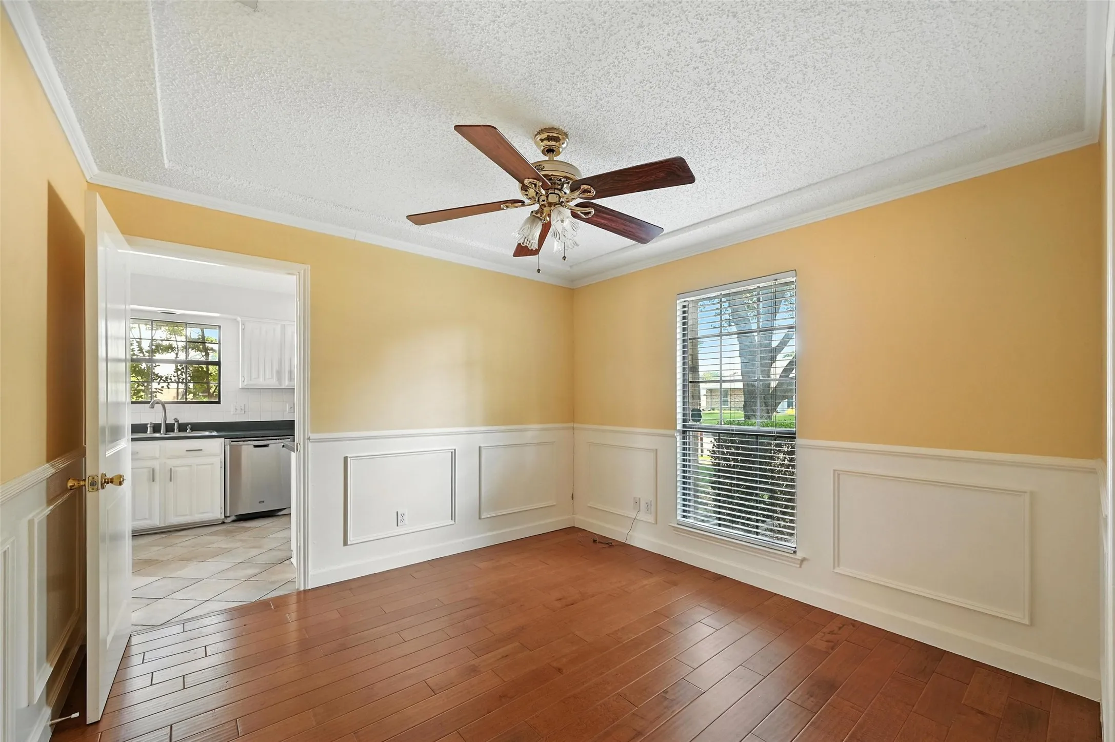 Bright and airy dining room showcasing warm yellow walls, classic wainscoting, and refinished hardwood flooring