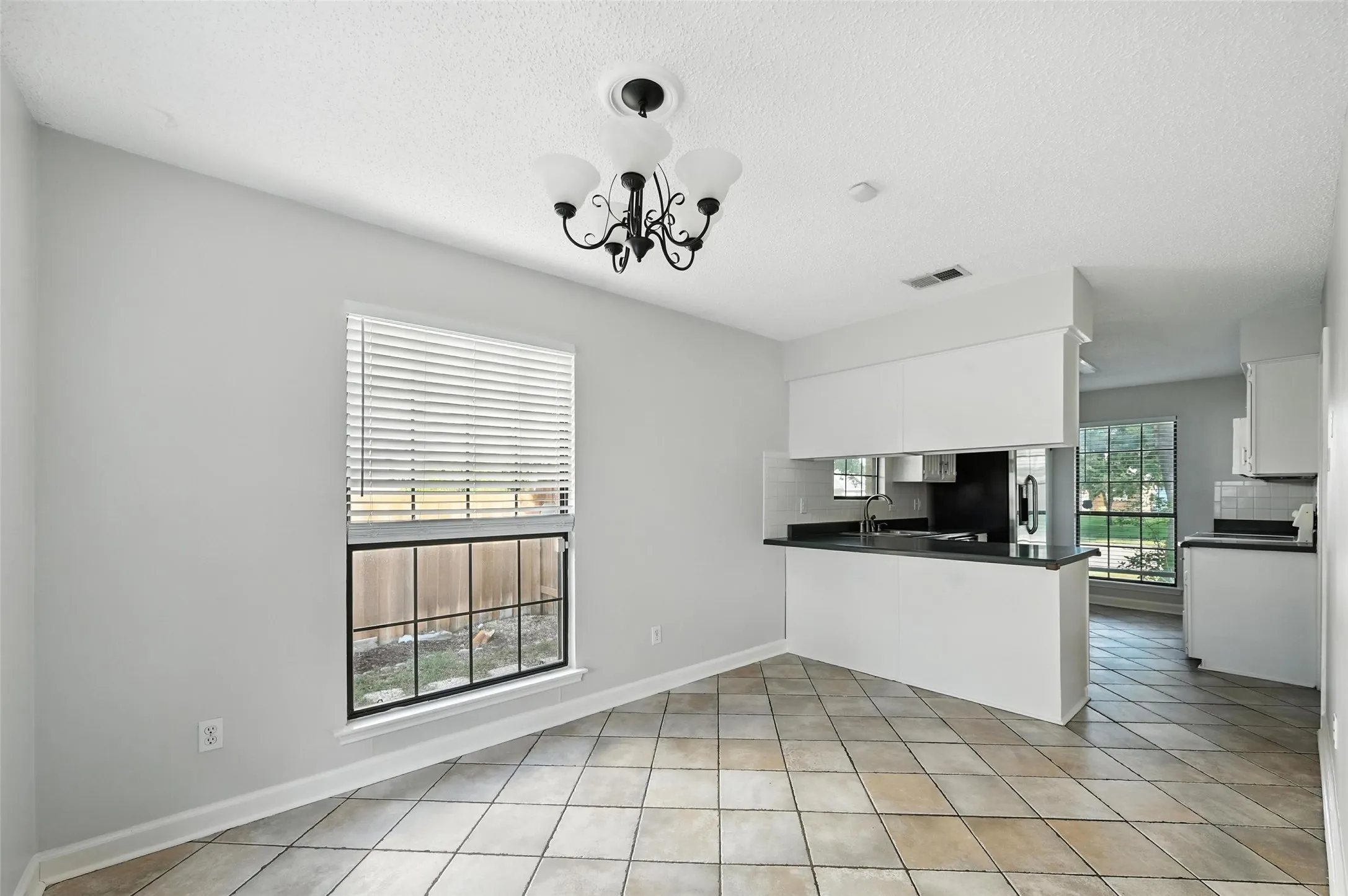Charming brick ranch home featuring a manicured front lawn, mature shade trees, and a welcoming center entry with black-trimmed windows and doors