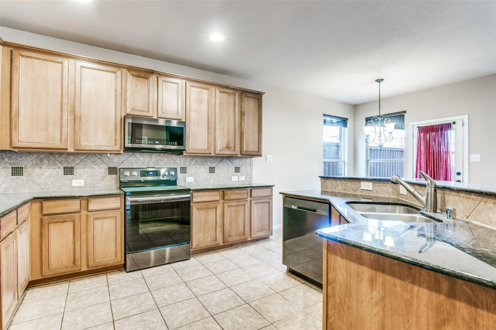 Kitchen featuring wood cabinetry, stainless steel appliances, granite-style countertops, and tile flooring