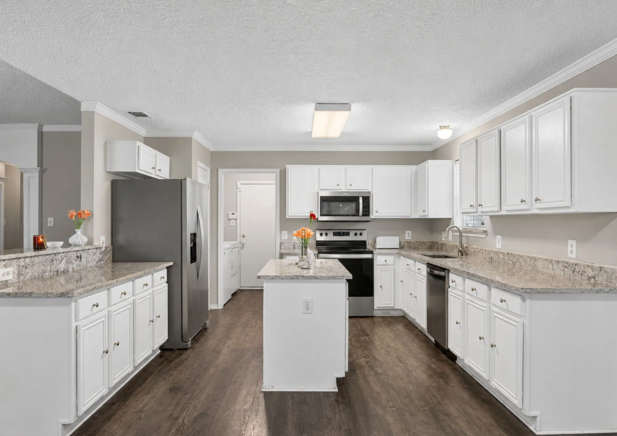 Spacious kitchen featuring white cabinetry, granite countertops, stainless steel appliances, a center island with prep space, and wood-finish flooring throughout