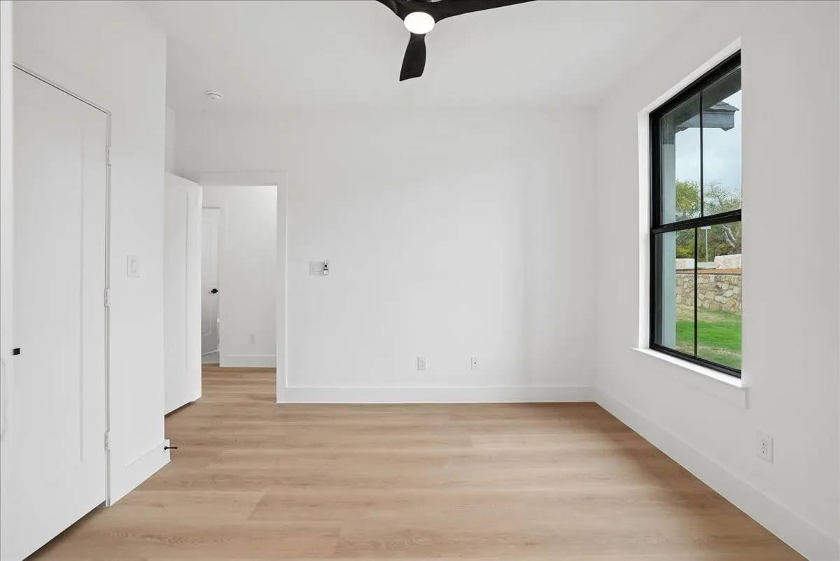 Recessed lighting, wood-finish flooring, white walls, and a black ceiling fan